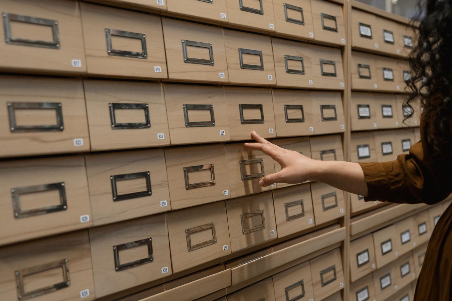 Persona organizando cajones de archivo, representando visualmente la función de los metadatos para organizar y encontrar información.